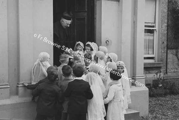 PARISH SCENE  GROUP OF CHILDREN WITH PRIEST ON DOORSTEP OF HOUSE